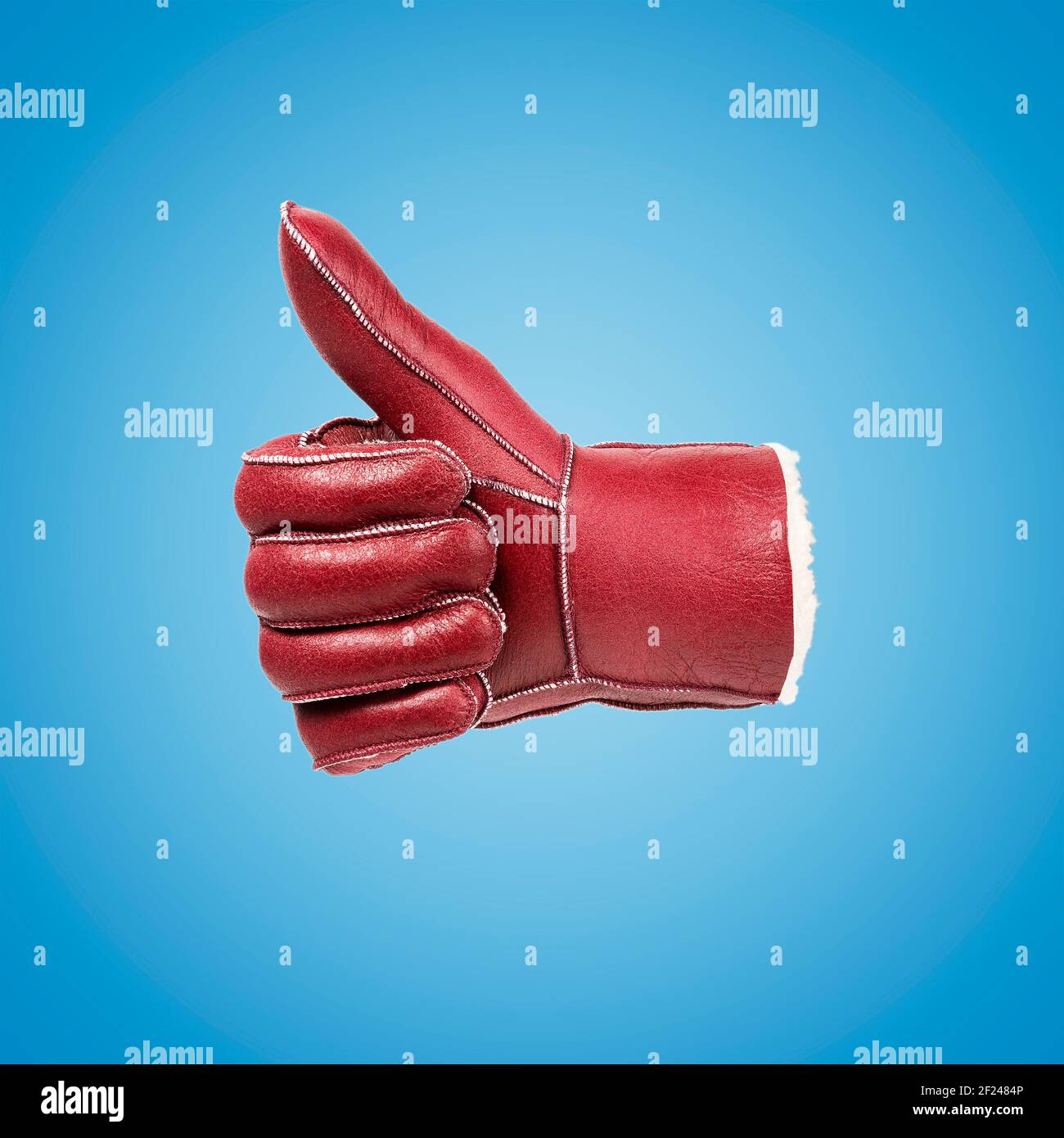 Gesturing red leather glove on blue background. Minimal art fashion concept. Stock Photo