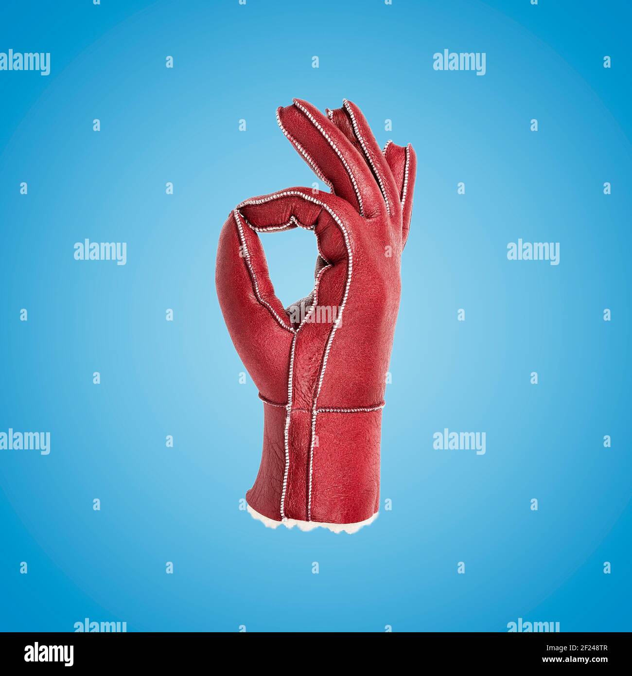 Gesturing red leather glove on blue background. Minimal art fashion concept. Stock Photo