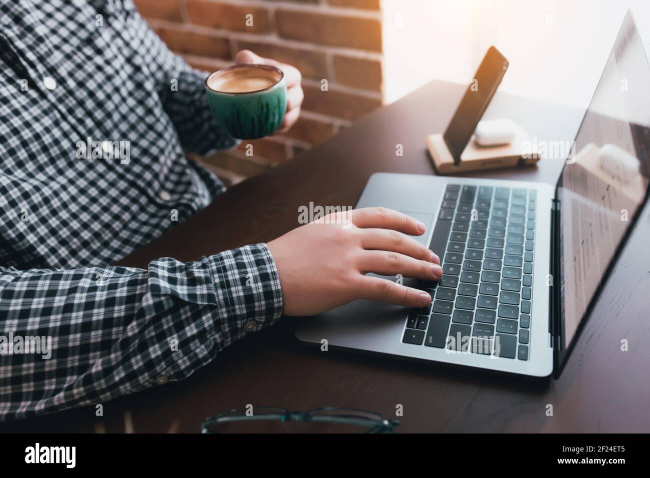 Man working at the laptop with a cup of coffee at home. Blurred background. High quality photo Stock Photo