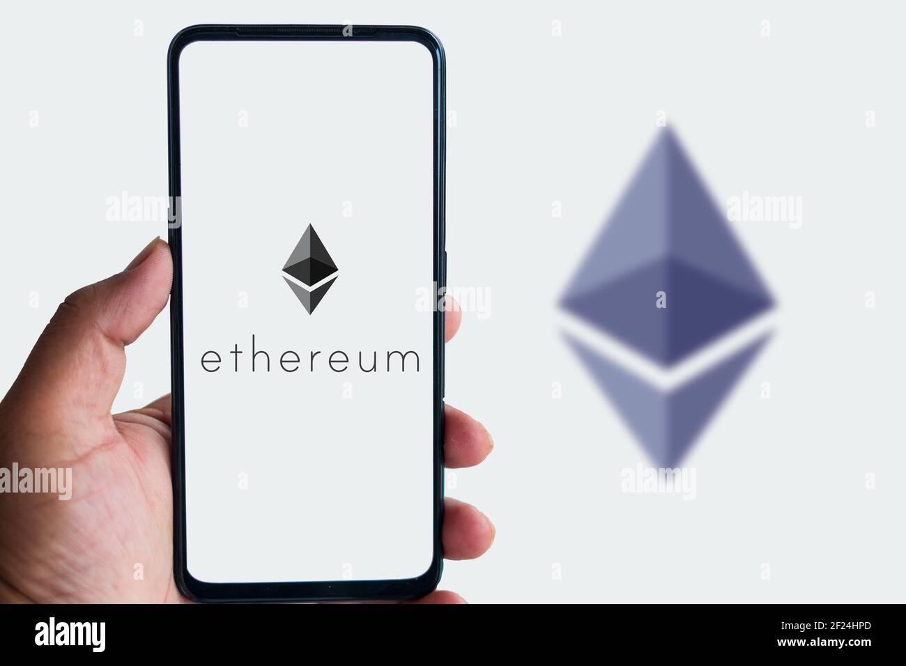 Man holding smartphone with Ethereum logo agains the isolated background. Stock Photo