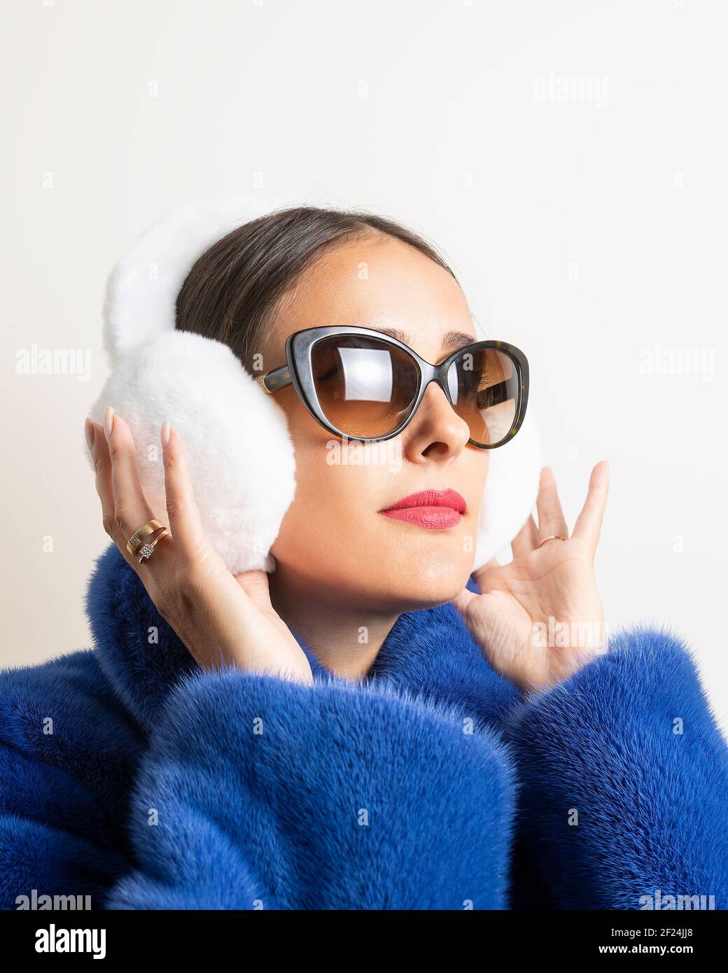 Winter fur earmuffs on woman in blue fur coat. Minimal fashion concept. Stock Photo