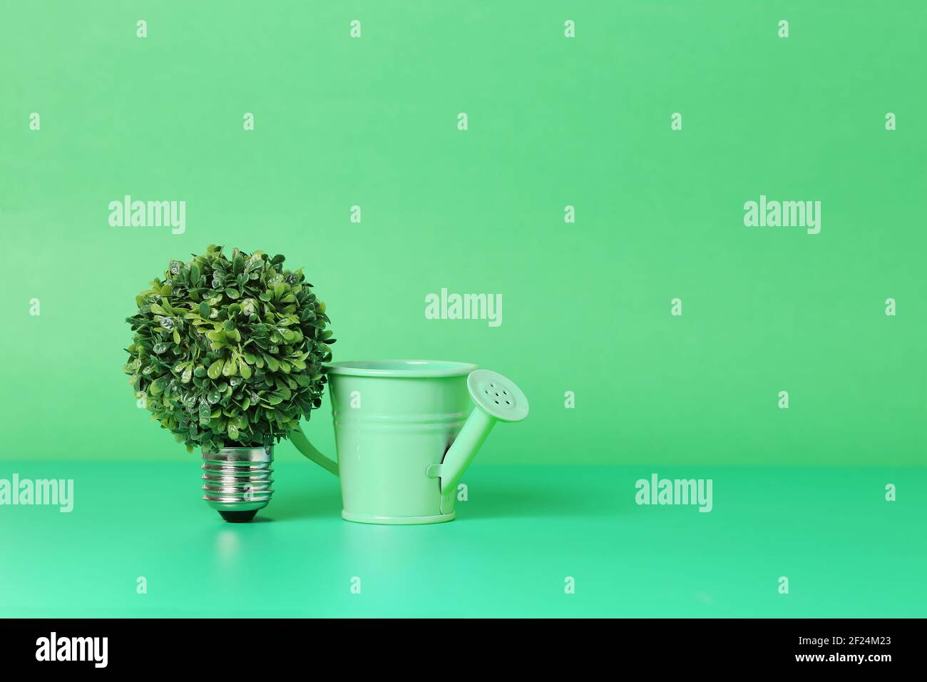 light bulb with tree and watering can on green, growth concept Stock