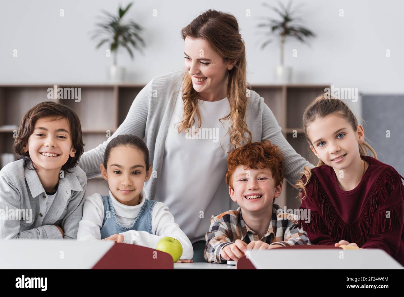 cheerful kids looking at camera near happy teacher in classroom Stock ...