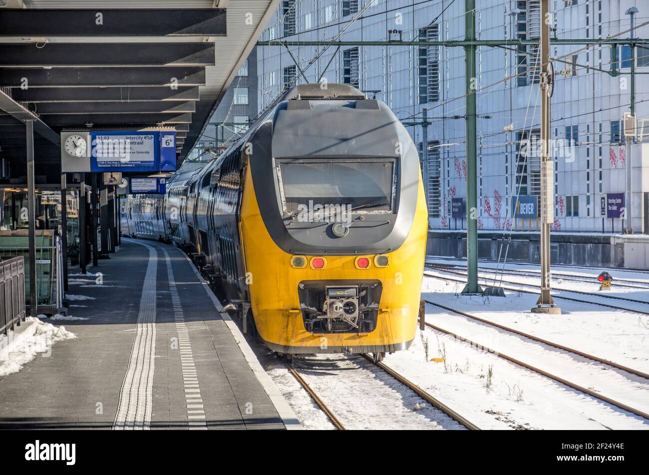 The Hague, The Netherlands, February 13, 2021: yellow Dutch Railways train leaving HS station bound for Amsterdam Stock Photo