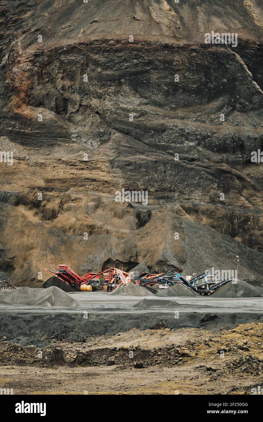 An aggregate mineral quarry and machinery with the open rock face in the background Stock Photo