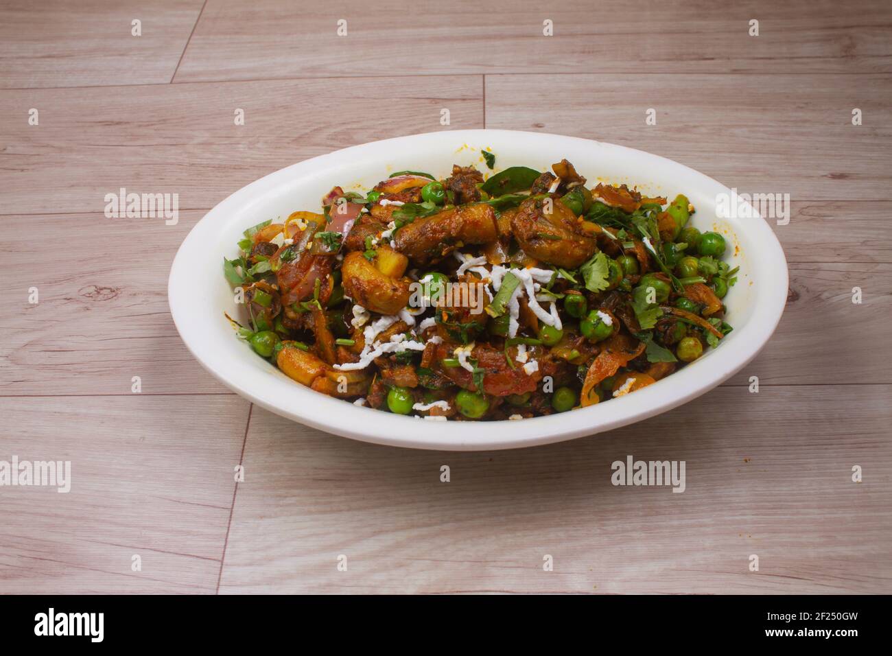 Paneer Chilis is an Indian dish, paneer cubes with tomatoes, onions, spring onions, chilli sauce. served on rustic wooden background, selective focus Stock Photo