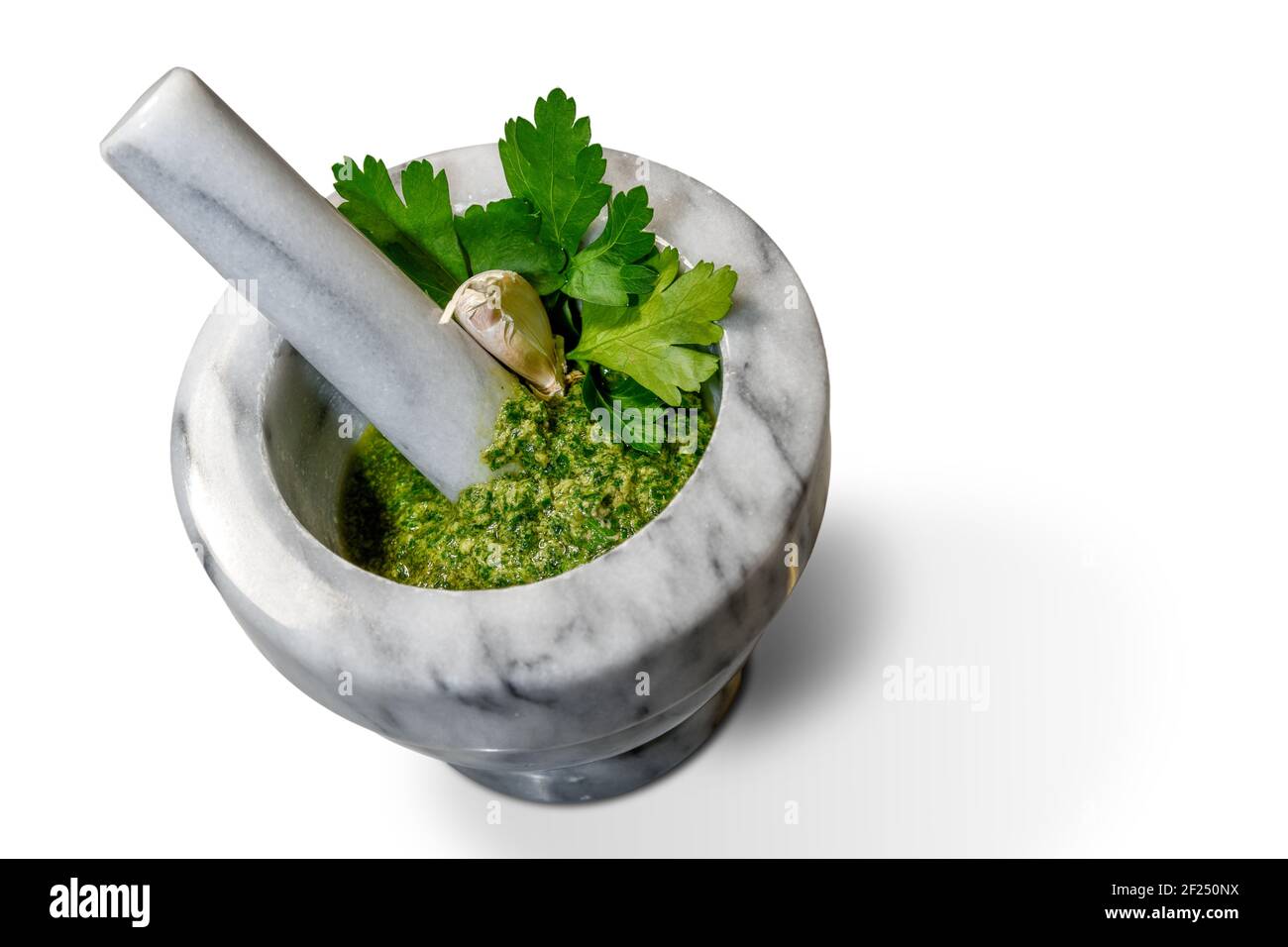 green sauce in marble mortar and pestle with parsley, garlic and extra virgin olive oil. Piedmontese sauce, Italy, in top view isolated on white Stock Photo