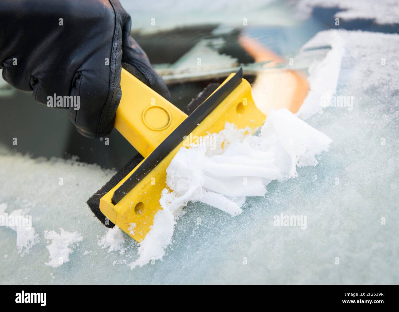 Close up shot of an ice scraper clearing a frozen car windscreen - London Stock Photo