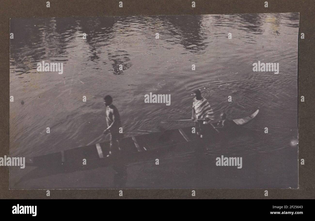Mannen in een kano.Two Surinamese men and a child in a canoe on the river. Part of a group of eleven album blades with family photos of the Gonggrijp family in Suriname, ca. 1912. Stock Photo