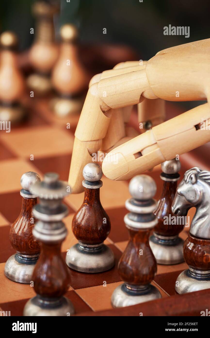 Cropped shot of robot hand playing chess, moving chess figure on chess board, selective focus. Concept of modern technology, strategy and tactic Stock Photo
