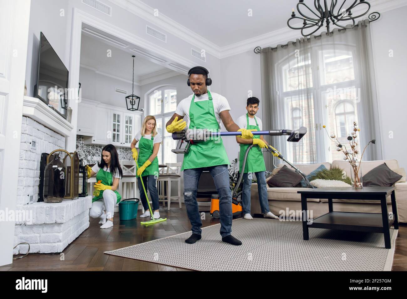 https://c8.alamy.com/comp/2F257GM/young-handsome-crazy-black-skinned-cleaning-service-man-in-uniform-having-fun-wearing-headphones-listening-to-music-and-dancing-with-vacuum-cleaner-2F257GM.jpg