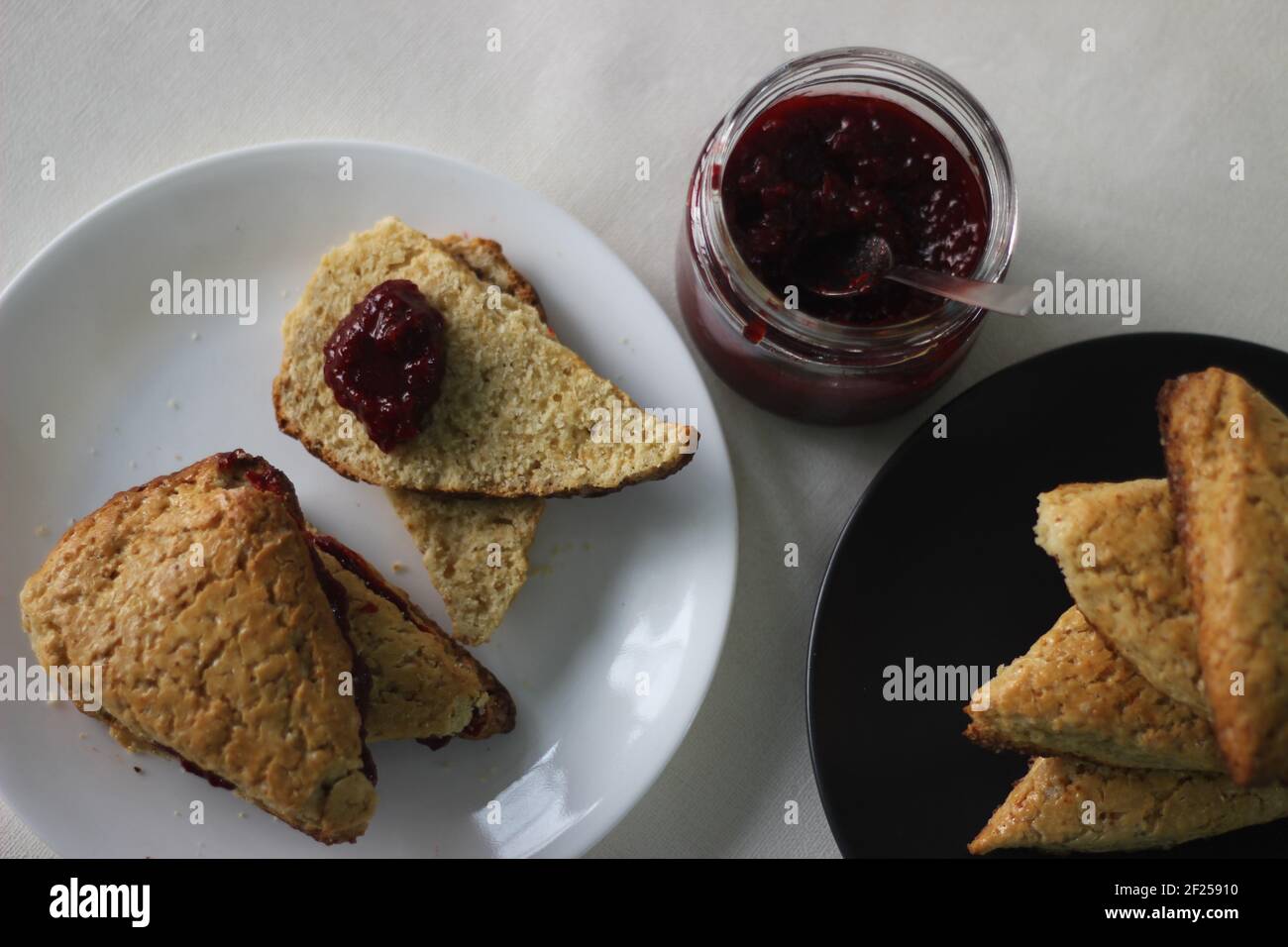 Home-baked plain mildly sweet buttermilk scones served along with homemade strawberry jam. Shot on white background Stock Photo