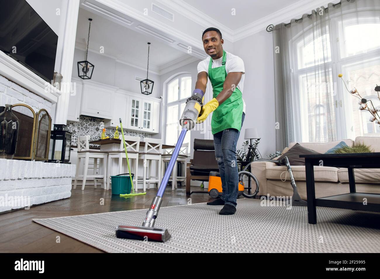 African man removing dust from carpet with vacuum cleaner Stock Photo
