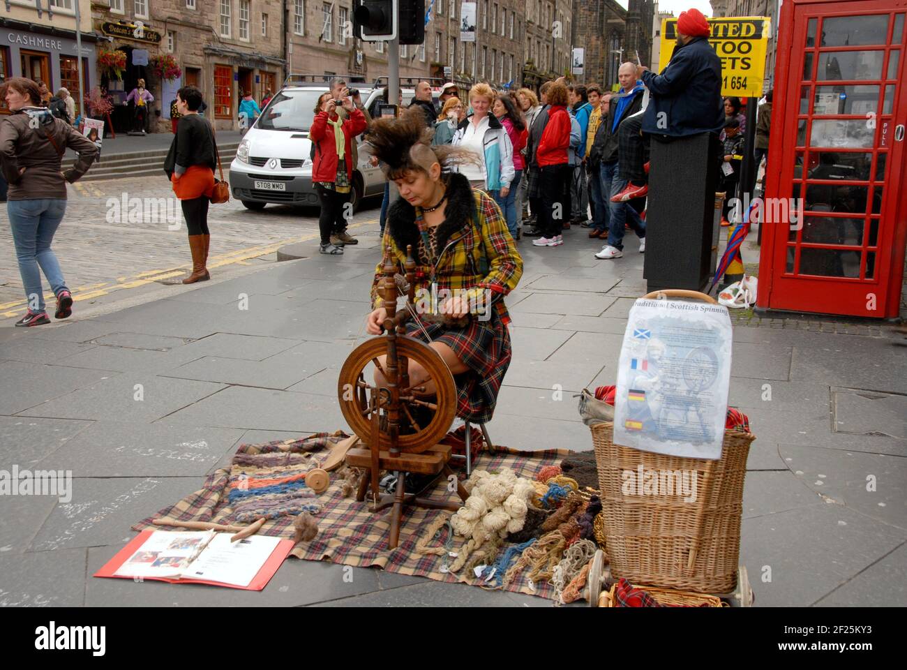 Woman demonstrating spinning in street at Edinburgh Fringe Festival, Edinburgh, Scotland. Multi-lingual sign suggests donation of £1 Stock Photo