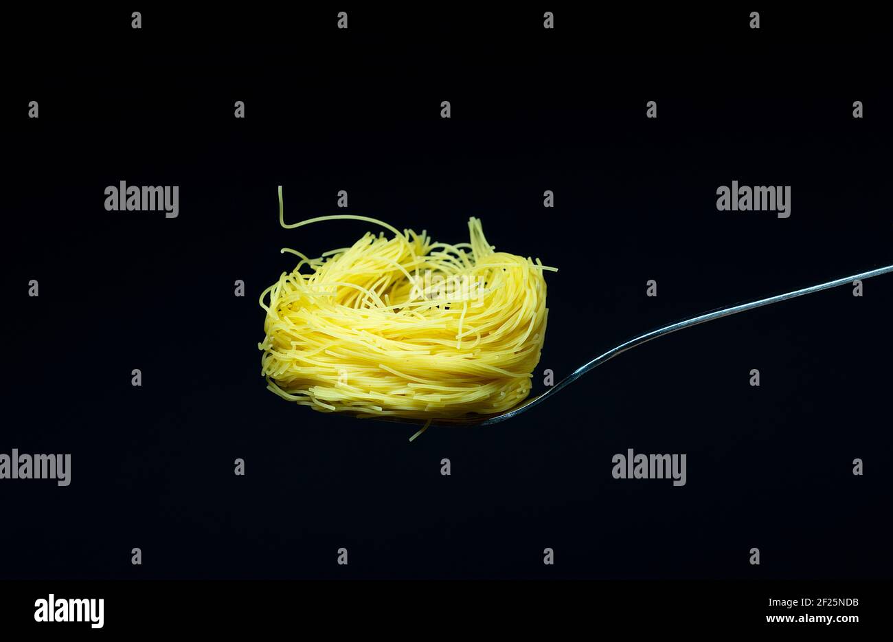 Abstract Variation Of Dried Raw Angel Hair Pasta In A Silver Metal Spoon Isolated On Black Stock Photo Alamy