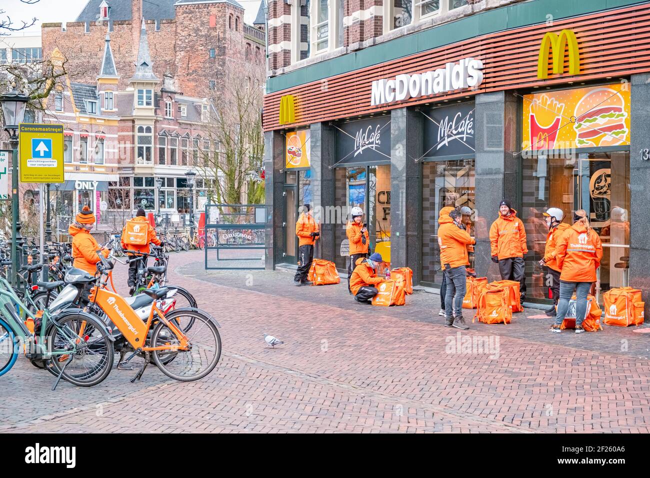 Utrecht Netherlands Thuisbezorgd and Deliveroo food couriers wait in Utrecht, Netherlands. Bicycle food delivery is popular in U Stock Photo