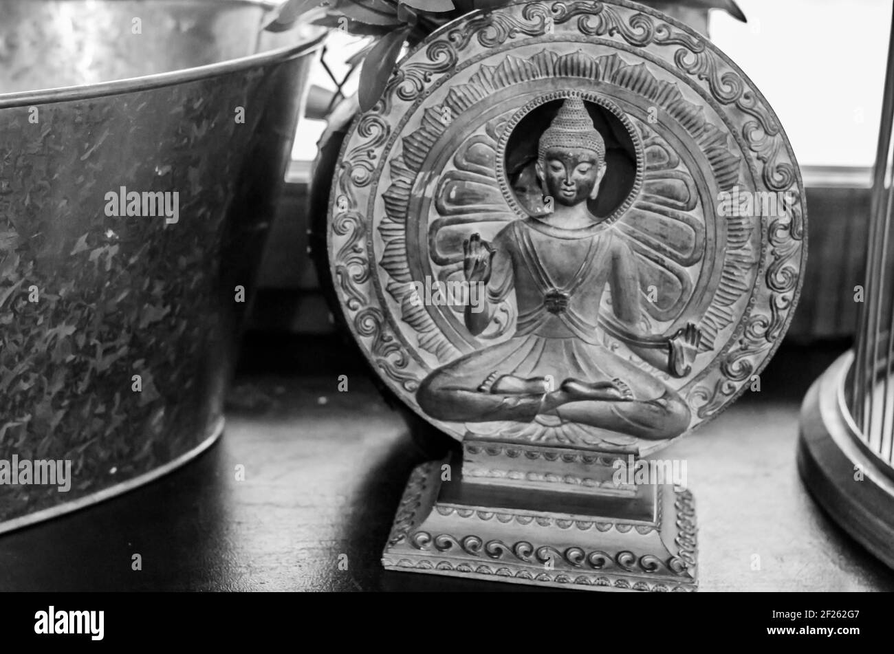 Buddha figurine on a background of bronze circles. Sacral figurine in the interior. Stock Photo