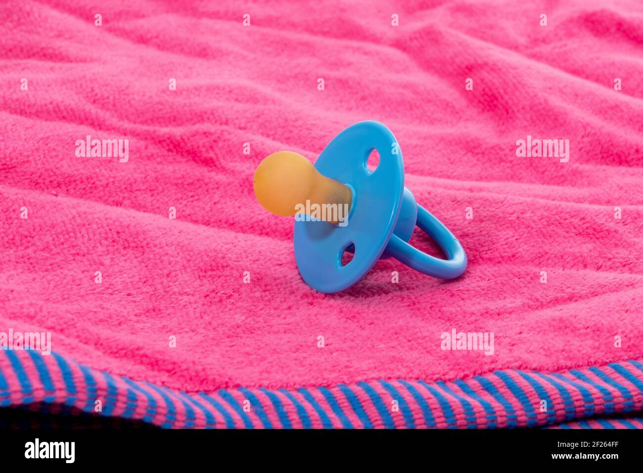 Babies pacifier placed on a pink towel Stock Photo