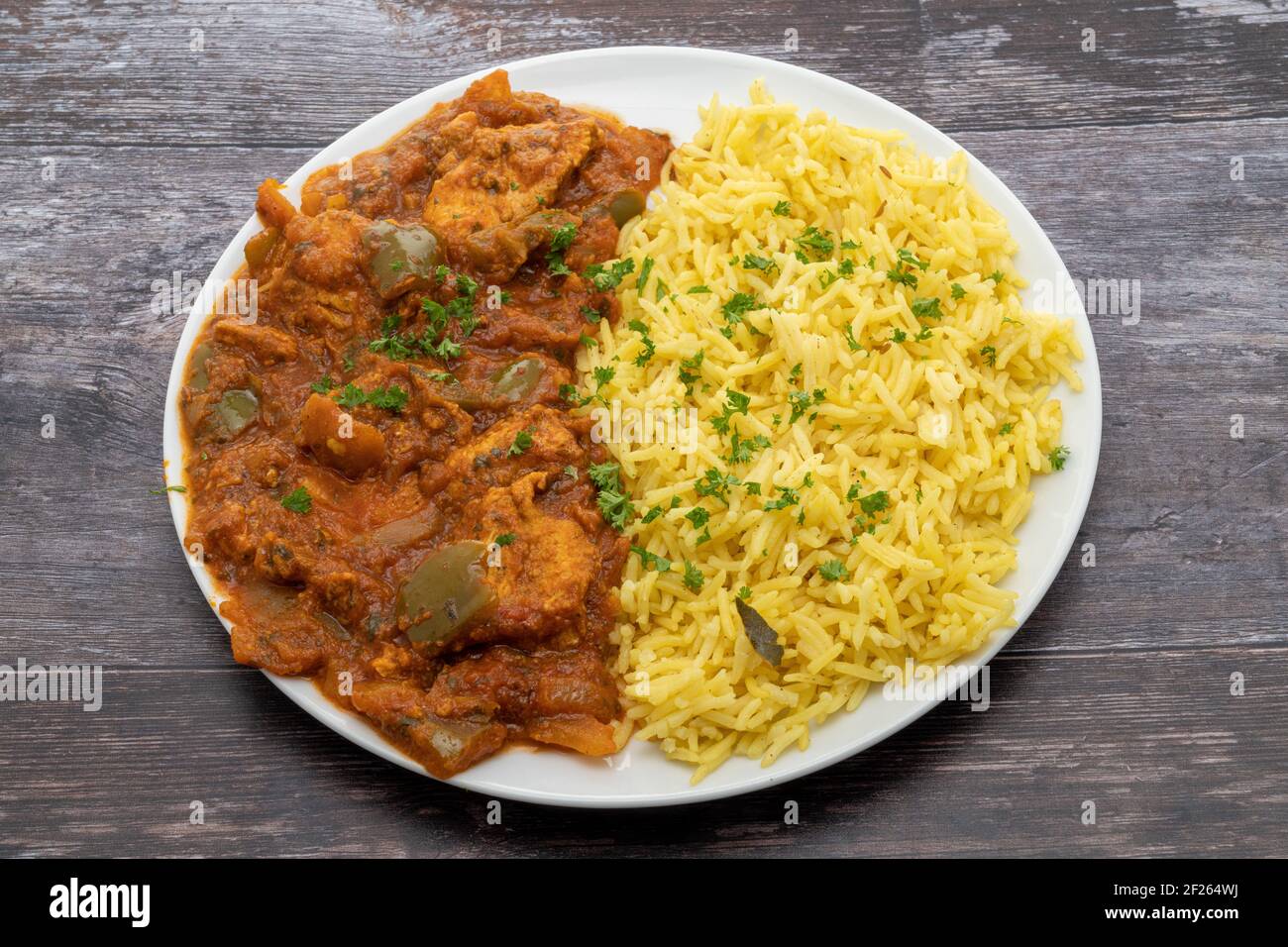 Chicken Jalfrezi with pilau rice served on a white plate Stock Photo