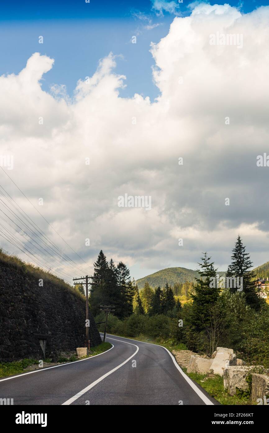 A vertical shot of an empty asphalt road through mountains under a ...