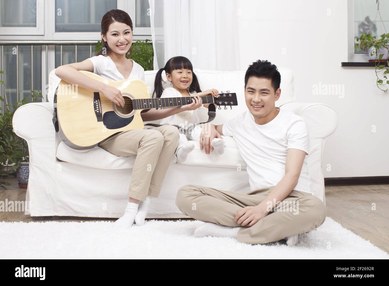 Young family playing guitar in living room Stock Photo