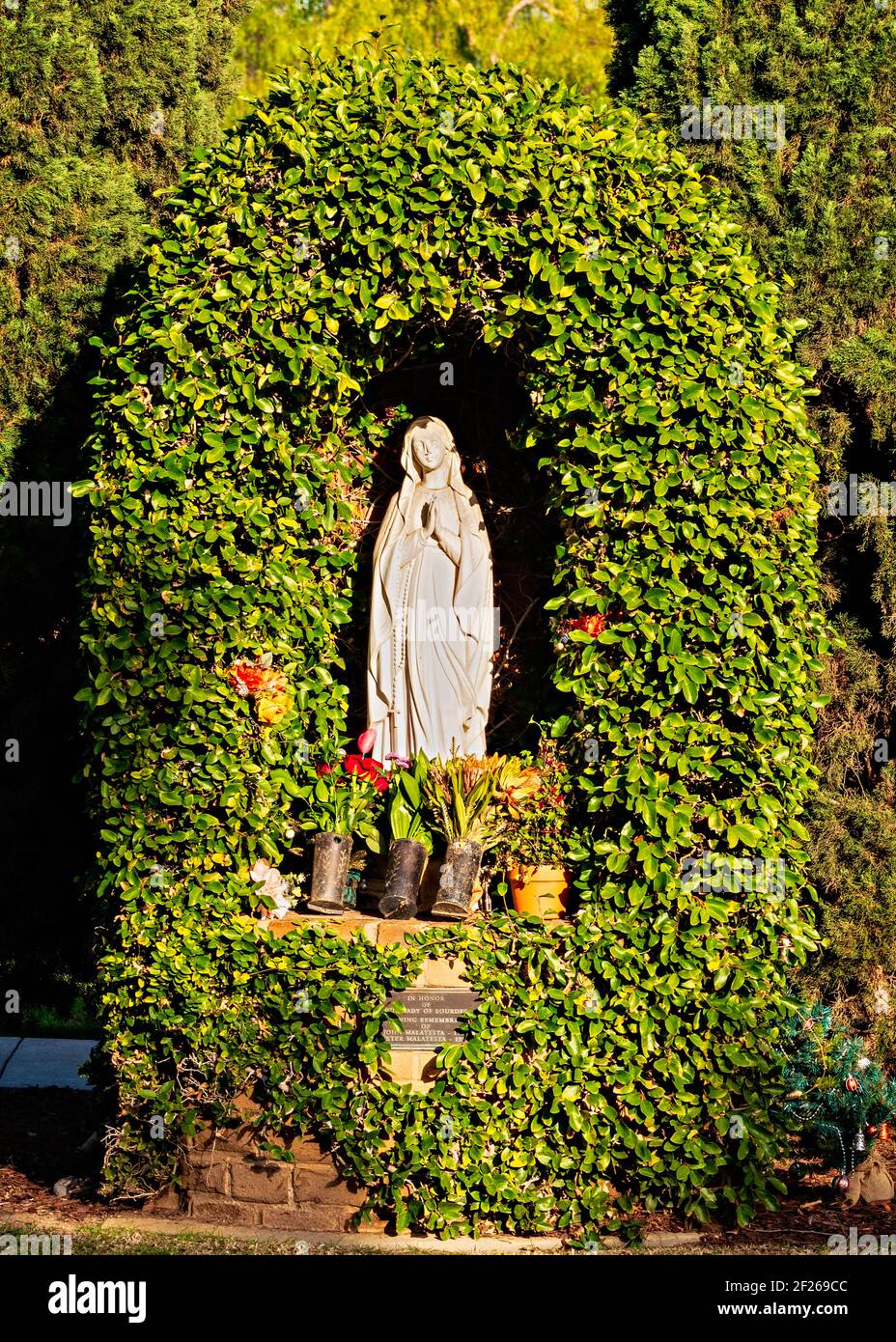Madonna statue in cemetery surrounded by sculptured hedges. Stock Photo