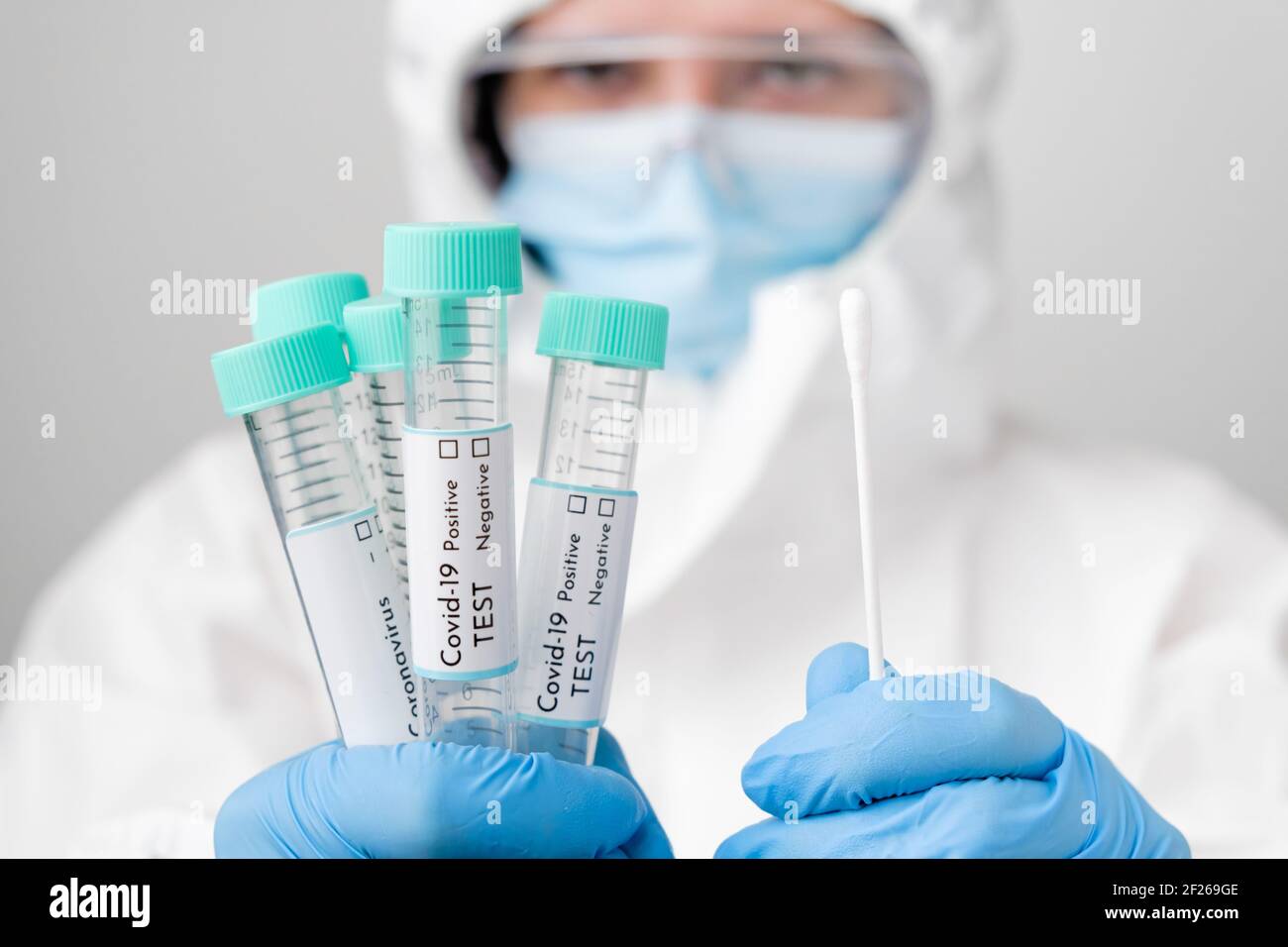 Doctor in PPE suit and face mask demonstrates test tubes with coronavirus Covid-19 samples. Stock Photo
