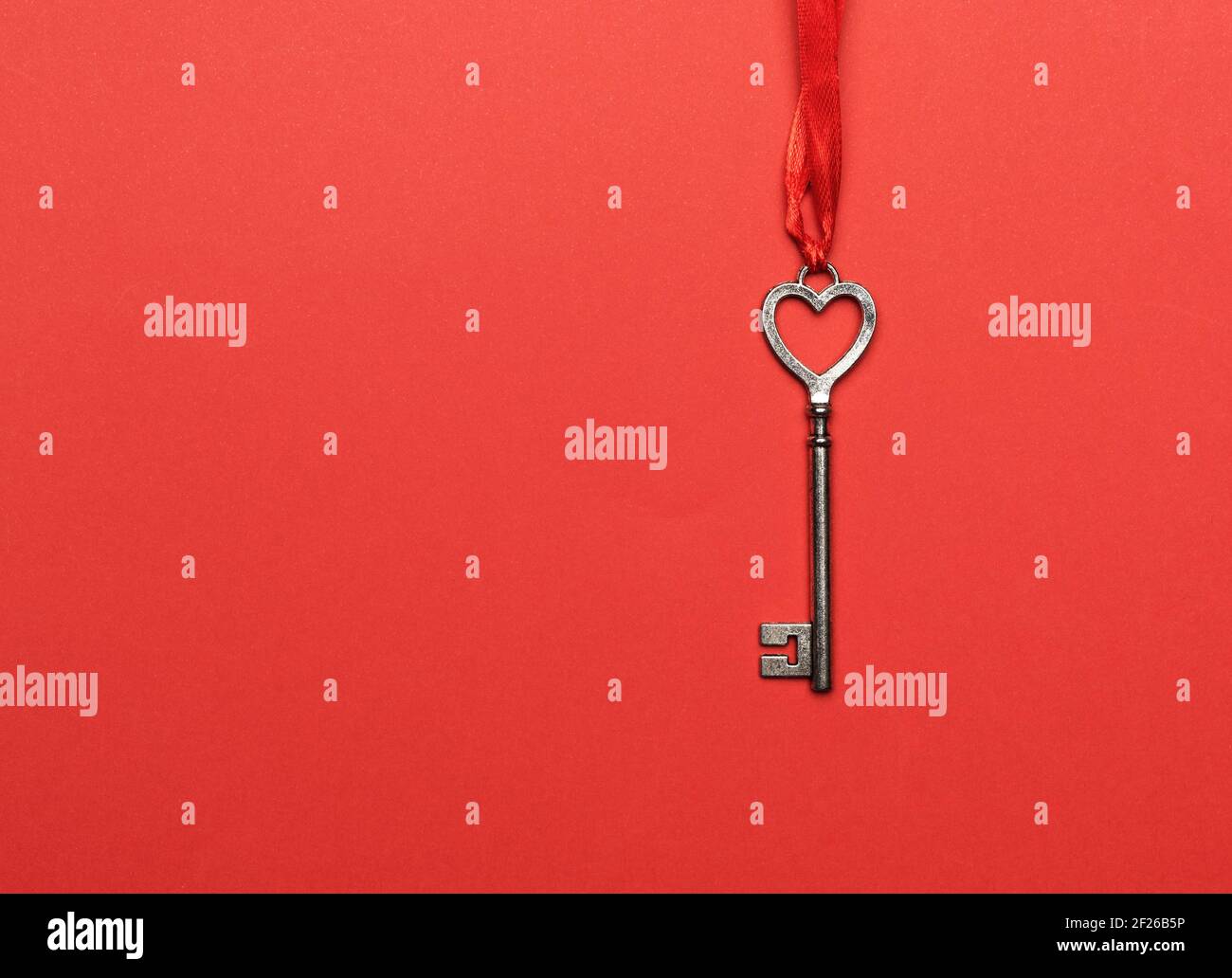 Metal key hanging on a red ribbon, red background Stock Photo - Alamy