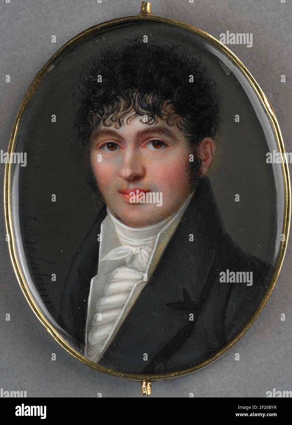 Portret van een onbekende man.Portrait of an unknown man. Oval portrait miniature in slippery golden list, representing a young man with dark curly, loose over the forehead falling. The person portrayed is shown against a dark gray background. The back is decorated with a two-tone hair decor, representing a corn sheaf. Part of the portrait miniaturen collection. Stock Photo