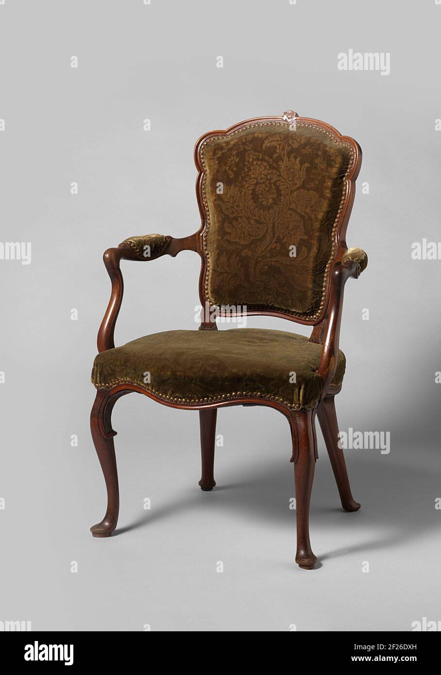 Chair. Muhogany armchair. The furniture is covered and rests on overhoeks, stretched S-shaped legs, which proceed in the seating room without interruption. The seating frame is hemisphere and sheltered at the front; Scalloped rule. The armrest struts have been placed backwards, stretched S-shaped and distinguish slightly. The C-shaped armrests have cushions. The healed back window rests on short struts. The styles are scalloped, as well as the upper shell, which has a stunned flower in the middle. Stock Photo