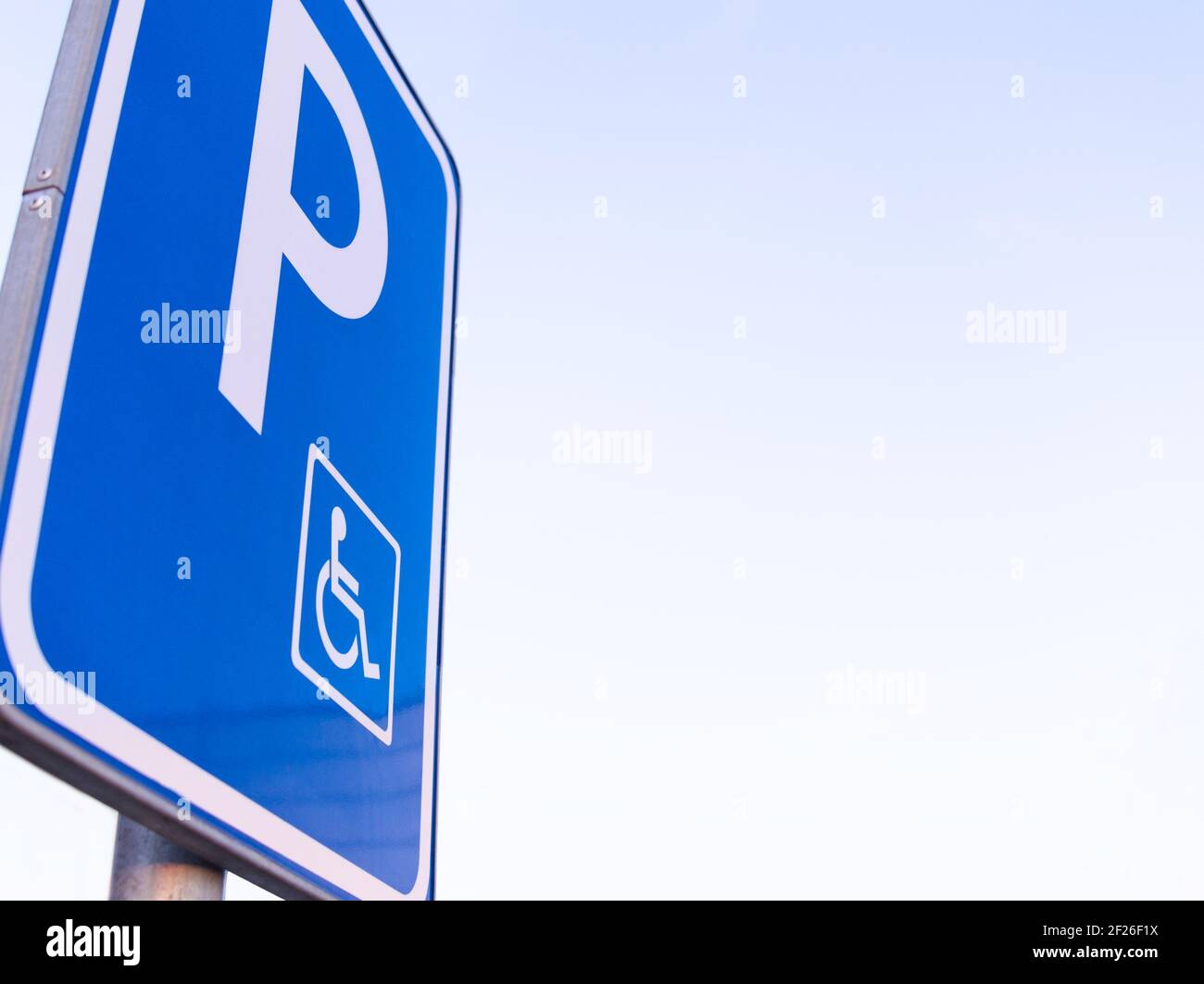 Low Angle Blue Disabled Parking Sign with Clear Sky Closeup Stock Photo
