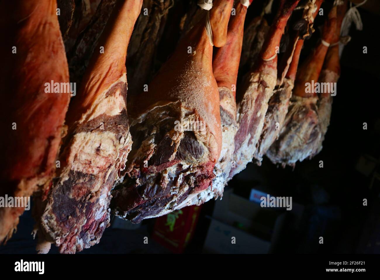 Smoked legs of ham in smokehouse. Whole ham hanging from the ceiling in farm. healing and drying of hams from Iberian pigs Stock Photo