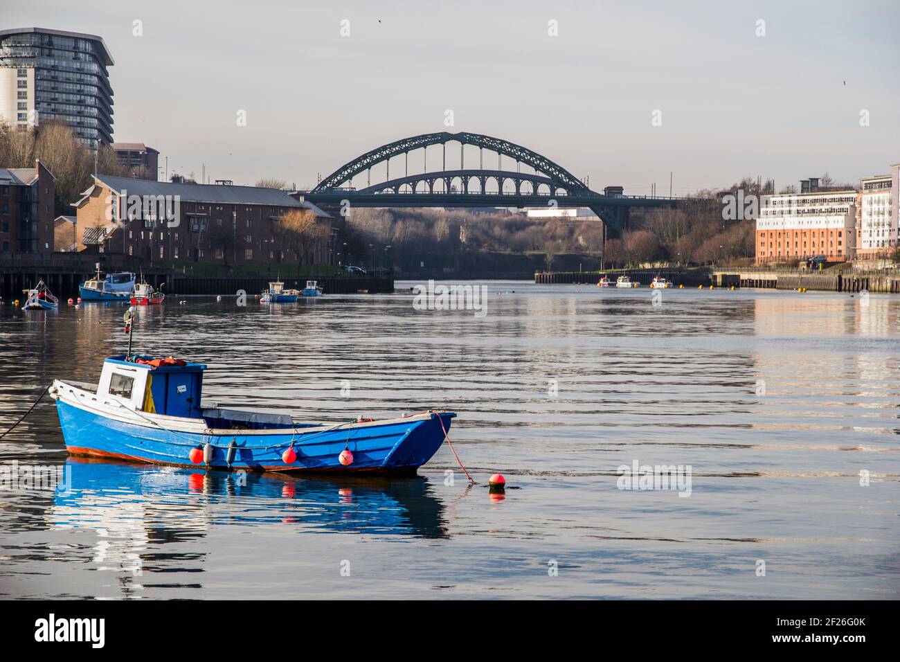 View of Sunderland’s sea fishing harbour with boatd reflecting in the still water and the iconic Wearmouth Bridge in the background Stock Photo