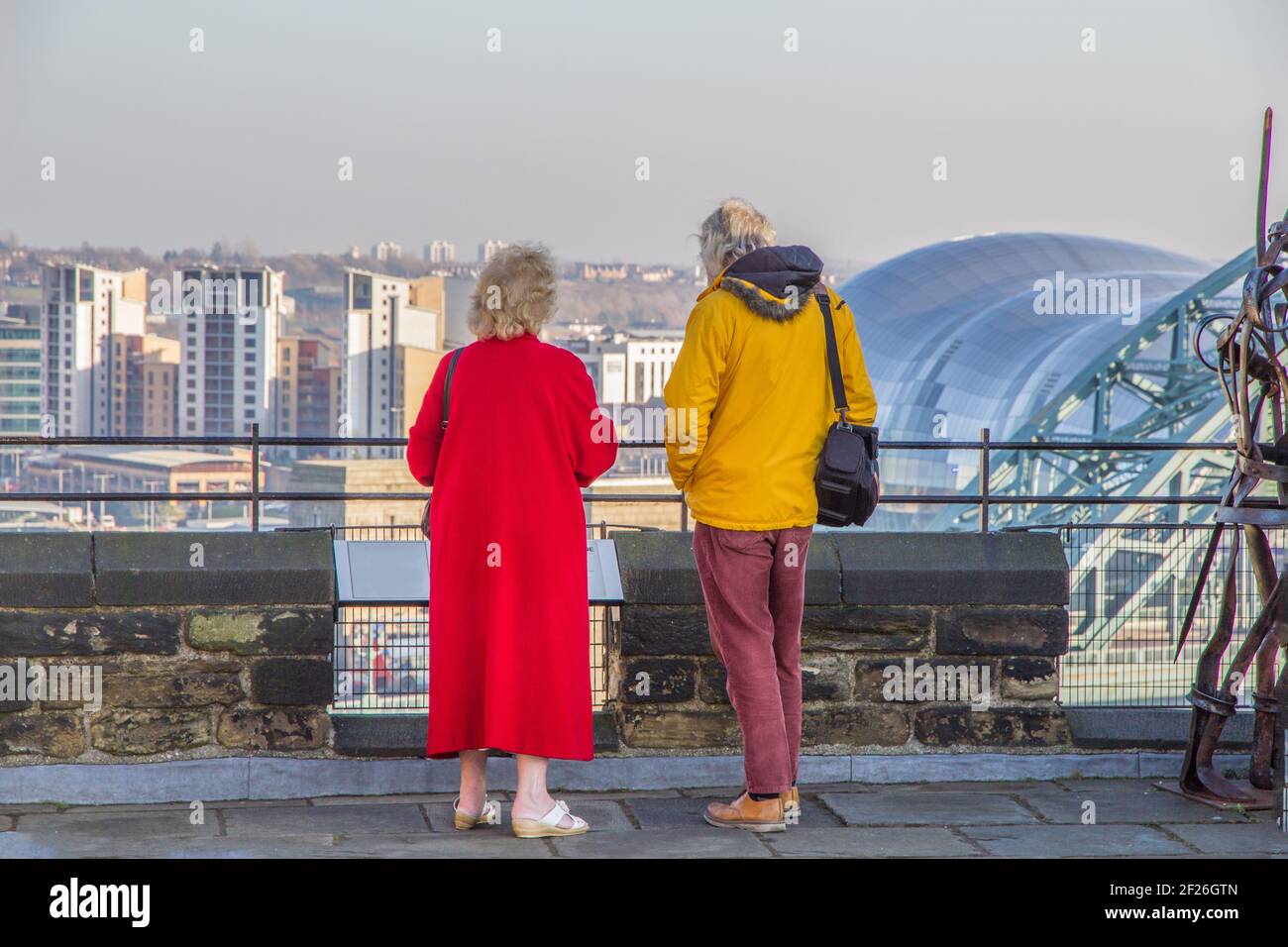 Pair of tourists in sharp focus admiring the view of Newcastle Upon Tyne famous landmarks such as the Tyne Bridge, art gallery, Gateshead music venue, Stock Photo