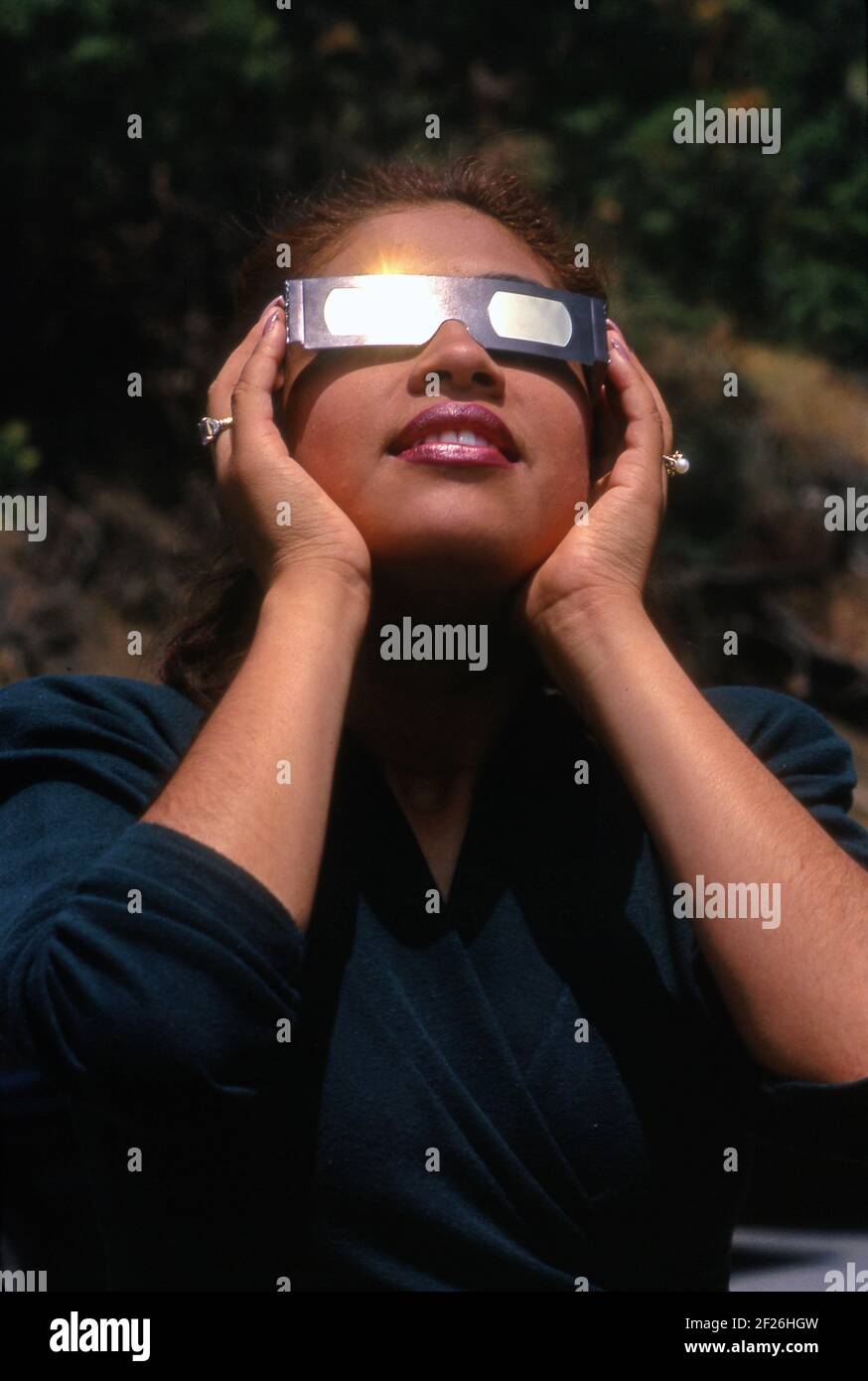 Woman with special glasses to protect her eyes is looking at a solar eclipse at the Griffith Observatory in Los Angeles, CA Stock Photo