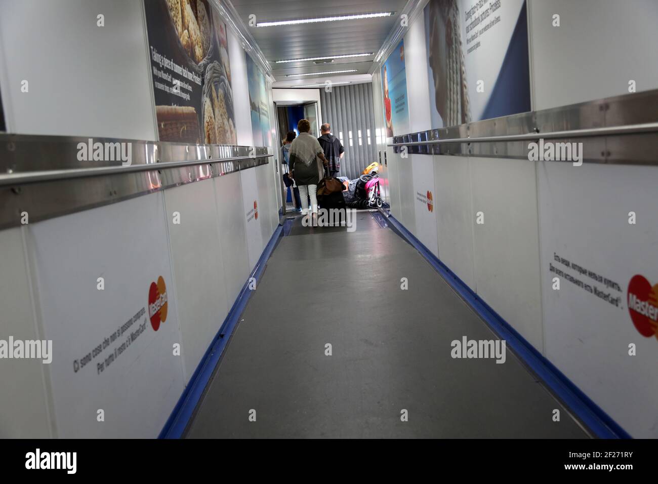 Heathrow Airport England Passengers on Jet Bridge boarding Aeroplane with Luggage to go in the hold - Luggage and Pushchair in pile on floor Stock Photo