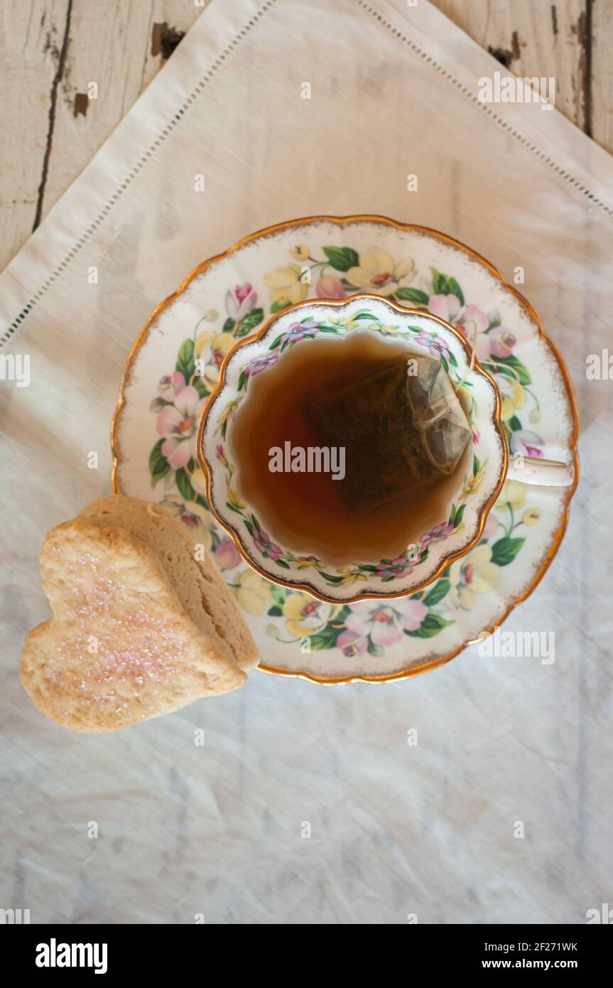 https://c8.alamy.com/comp/2F271WK/cup-of-tea-from-above-close-up-vintage-tea-cup-and-saucer-with-steeping-teabag-and-heartshaped-scone-on-vintage-white-irish-linen-2F271WK.jpg