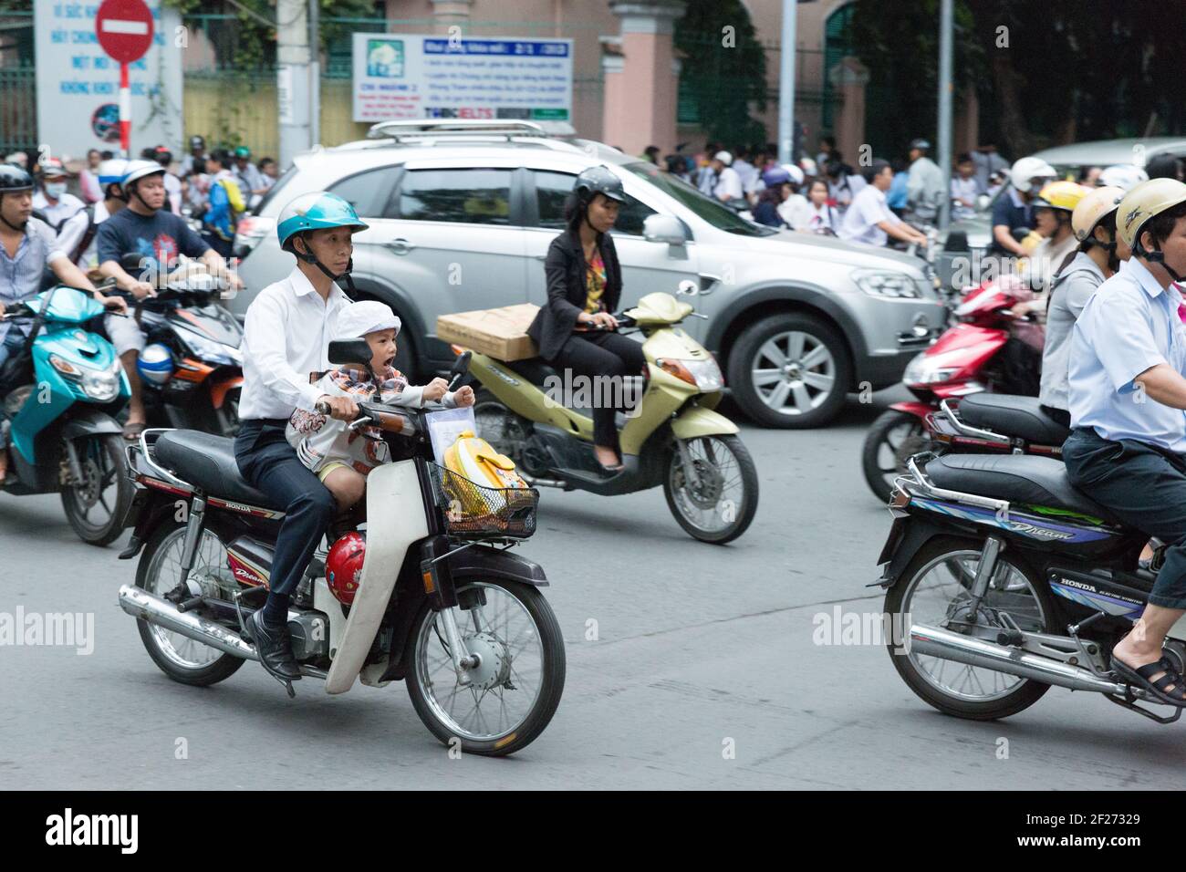 Vietnam, Ho Chi Minh City - Father and son on a scooter filled with other scooters during the early evening commute. Stock Photo
