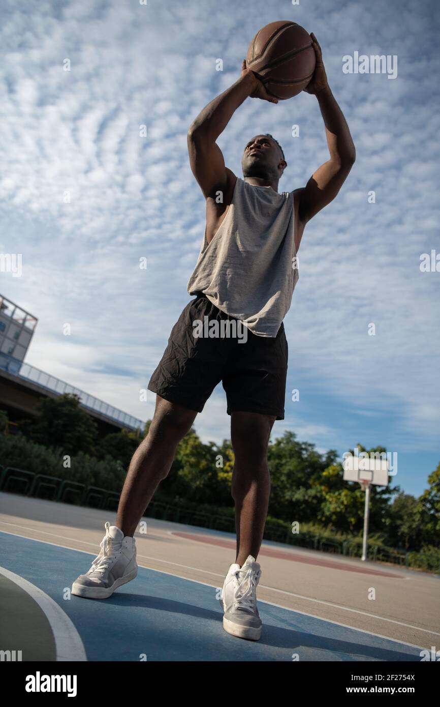 Muscular African American man scoring on basketball court Stock Photo