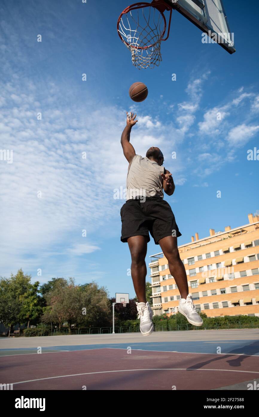 African American player jumping under basketball hoop Stock Photo