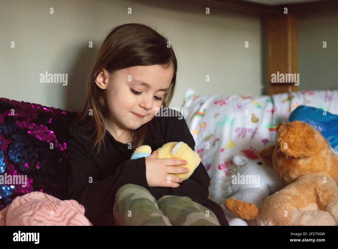 Little girl sitting on bed holding stuffed animal Stock Photo - Alamy