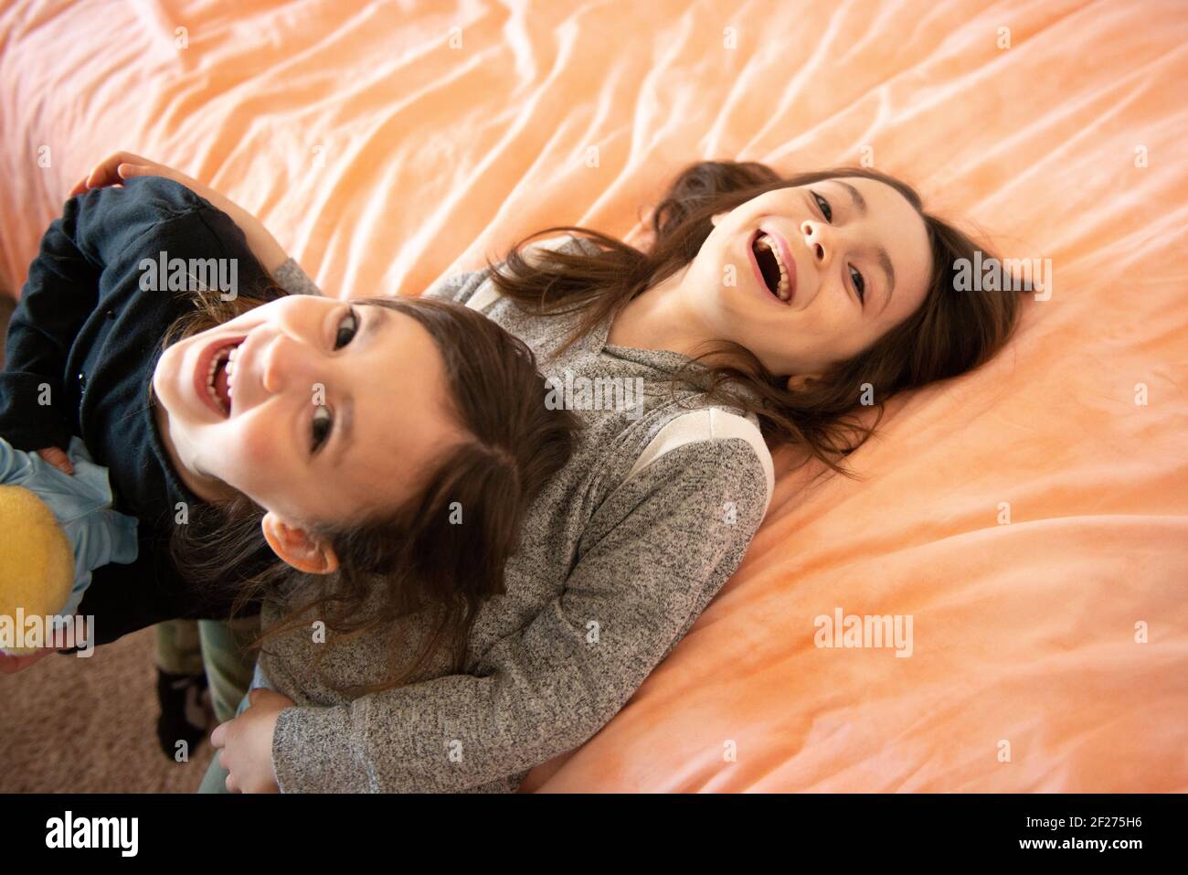 Two young girls laughing and playing in their bedroom. Stock Photo