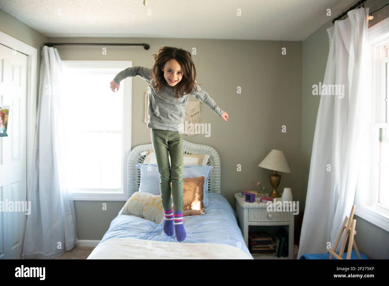 Little girl jumping on the bed in sunny bedroom Stock Photo Alamy
