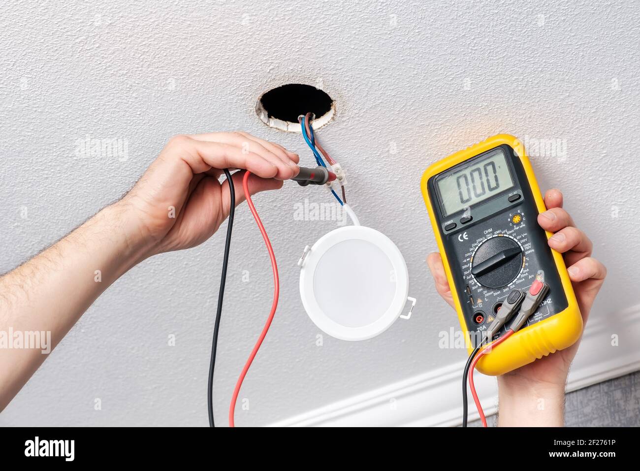 Electrician hands check with tester power supply before installing LED light Stock Photo