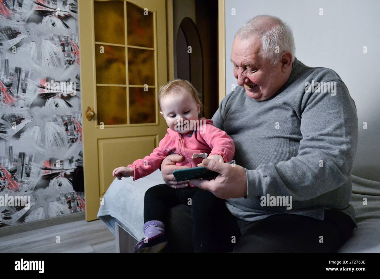 grandfather playing on mobile phone with little girl Stock Photo
