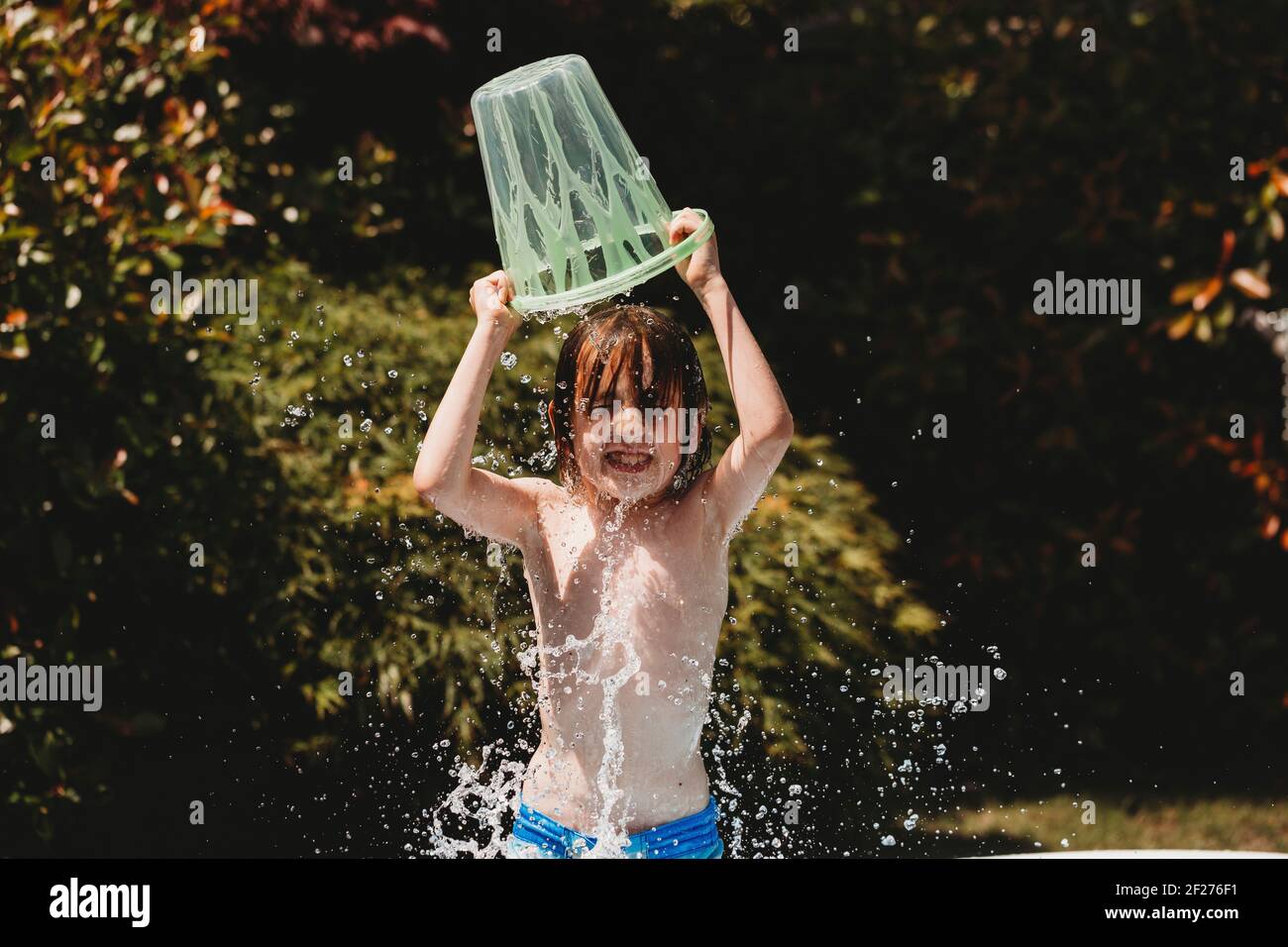 Boy standing pouring bucket of water over his own head Stock Photo Alamy