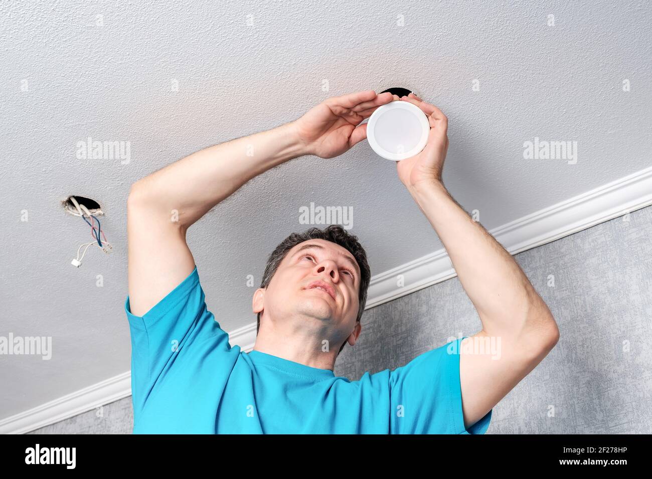 electrician installing LED spotlights on the ceiling Stock Photo