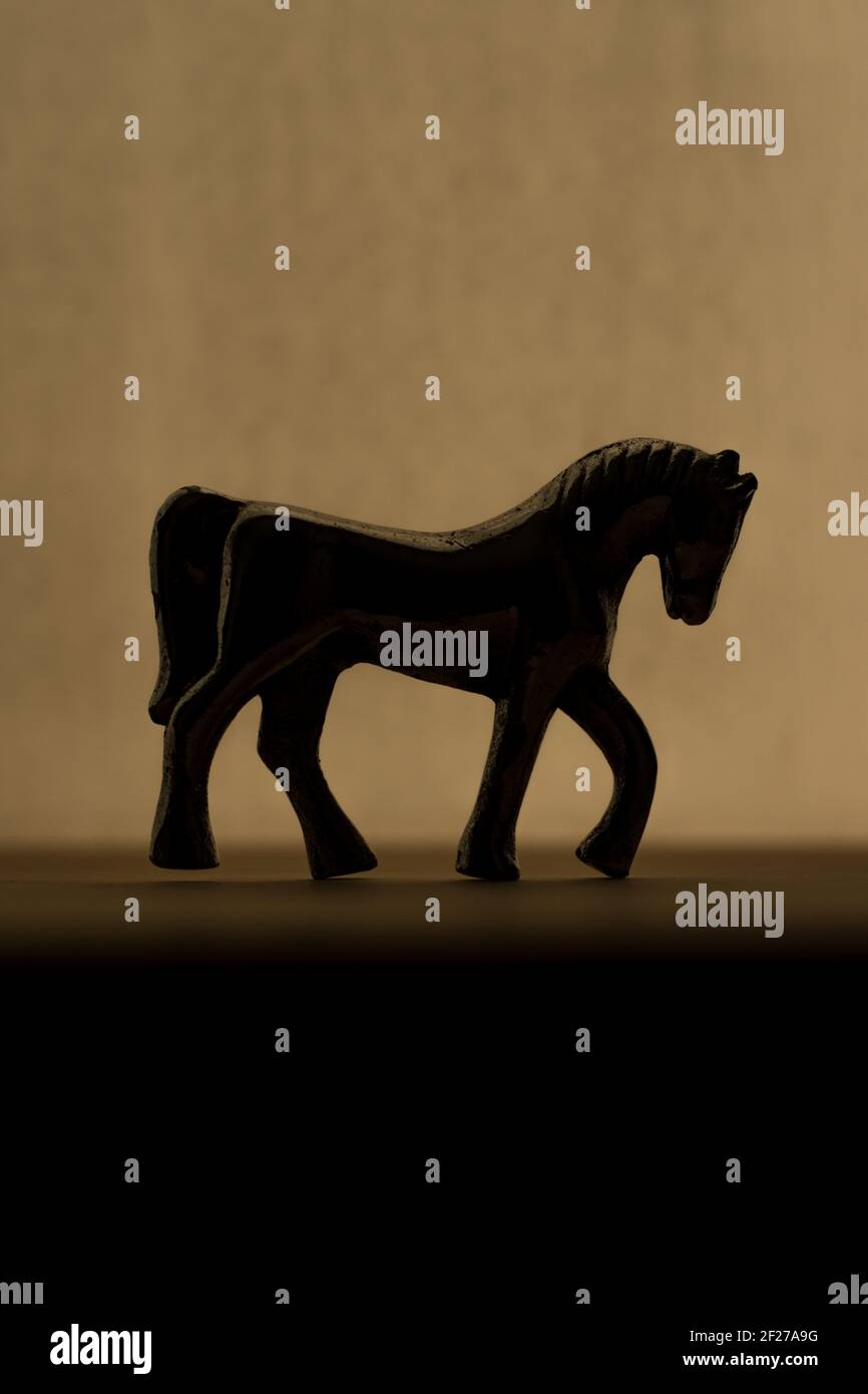 Horse sculpture silhouette in the darkness on a wooden surface Stock Photo