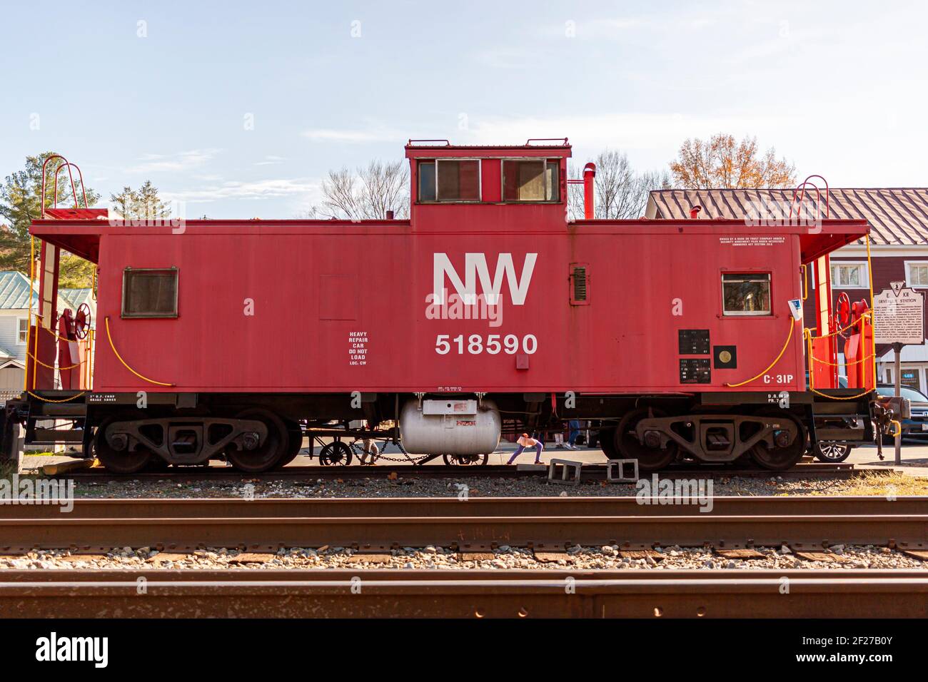 Clifton, VA, USA 11-14-2020: A red vintage caboose placed by the train tracks in front of the historic Devereux Station in scenic Clifton. This is an Stock Photo
