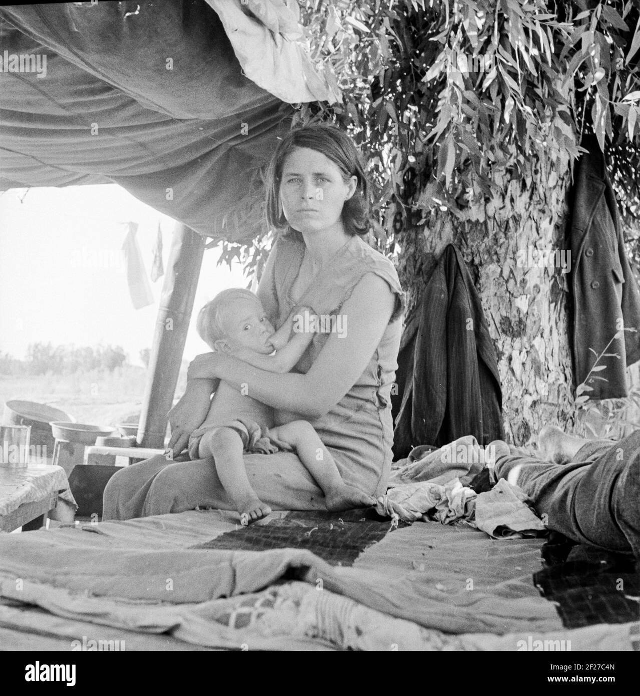 Photograph shows Zella (McCann) Power, wife of Jess Power with their baby Jesse Power. Drought refugees from Oklahoma camping by the roadside. They hope to work in the cotton fields. The official at the border (California-Arizona) inspection service said that on this day, August 17, 1936, twenty-three car loads and truck loads of migrant families out of the drought counties of Oklahoma and Arkansas had passed through that station entering California up to 3 o'clock in the afternoon . August 1936. Photograph by Dorothea Lange Stock Photo